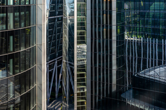 Cluster of high-rise buildings with vertical structures and mirrored reflections in London, showcasing symmetry, transparency, and modern urban design.