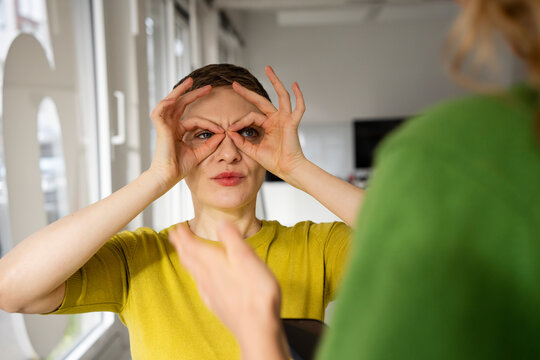 Two people in an office setting engaging in a playful and imaginative gesture