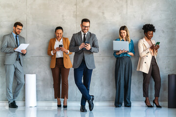 Busy smiling executive business team using digital devices in office. Diverse professional people