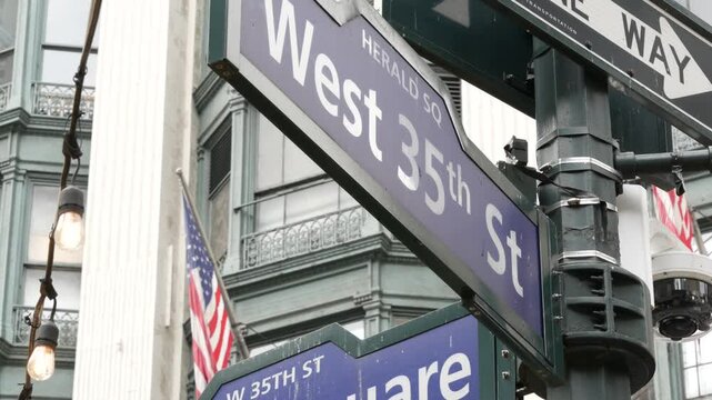 New York City crossroad, Manhattan Broadway street intersection road sign. NYC Midtown district architecture, Herald Square park, 6 Sixth avenue, United States. American flag. One way arrow road sign.