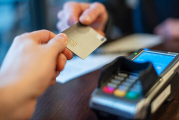 Hands exchanging a credit card for payment at a point of sale terminal