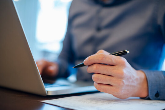 Businessman using laptop and holding credit card in office