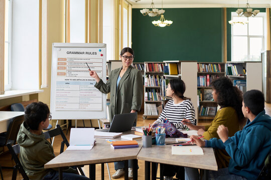 Young teacher conducting a language lesson for an intercultural group in a classroom