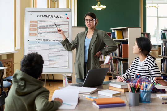 Female teacher communicating with group during language class in a classroom setting