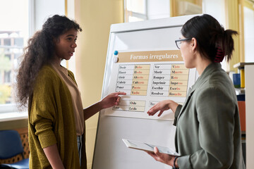 Student answering to teacher by board in language class