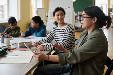 Teacher communicating with student during group class at desk