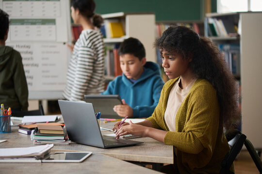 Students using digital devices during a group study session in a library