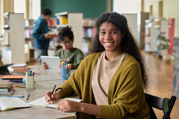 Girl studying at desk in group class with classmates in the background
