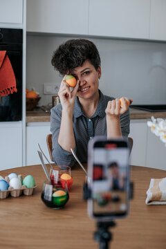 Woman vlogging a tutorial on dyeing Easter eggs in the kitchen