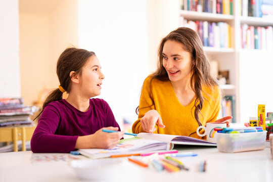 Big sister and little sister drawing together at home