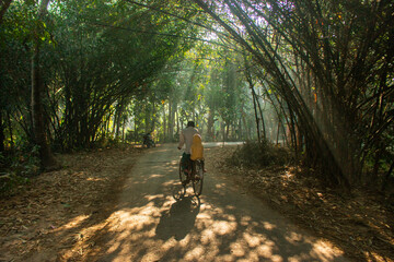 Father and son riding bicycle in a village road during morning.