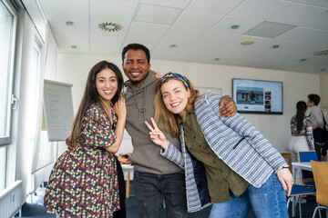 Three students standing in a multicultural classroom smiling and enjoying a positive learning environment