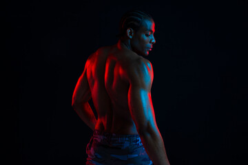 Athlete with muscular body in colorful lighting during workout