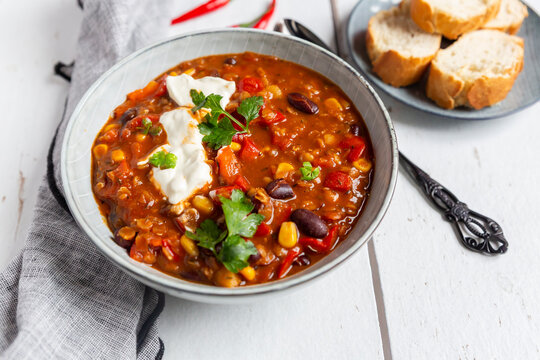 Bowl of vegetarian red lentil chili sin carne with bread on a wooden table