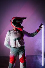 Portrait of a female motorcyclist in a helmet illuminated by vibrant neon lights in a dynamic pose