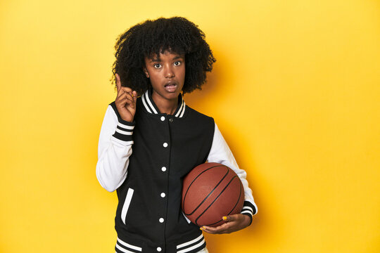 Vibrant teen girl with basketball on yellow studio background having some great idea, concept of creativity.