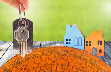 House key in girl hand with wooden house model and old Chines Fengshui compass over blurred green background, buy new property