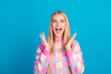 Happy Young Woman Smiling and Gesturing Exuberantly on Blue Background Wearing Stylish Colorful...