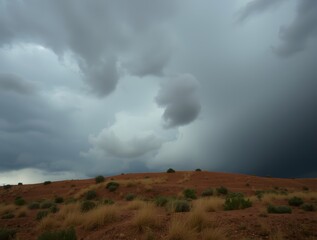 Dramatic clouds loom over a rugged desert landscape with sparse vegetation under an ominous sky