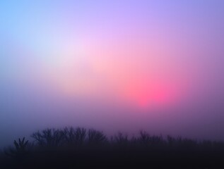 Fototapeta premium Ethereal sunrise casting soft hues over a foggy landscape with silhouetted trees in the foreground