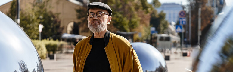 A dapper senior man embraces his trendy outfit while enjoying a leisurely walk.
