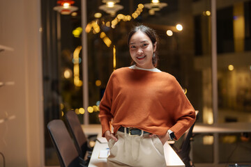 Young asian businesswoman smiling in modern office at night