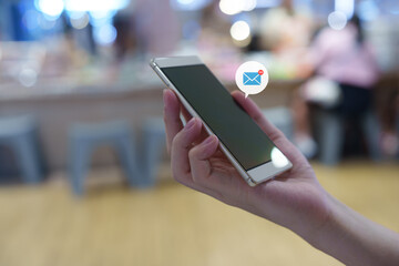 Email message, online communication, digital marketing, and mobile technology concept. Close-up of a hand using a smartphone to check emails with a notification icon displaying 99 new messages.