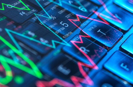 Stock market data and graphs overlaid on a computer keyboard