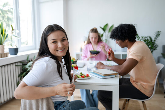 Asian woman smiling at camera while having lunch with friends indoors