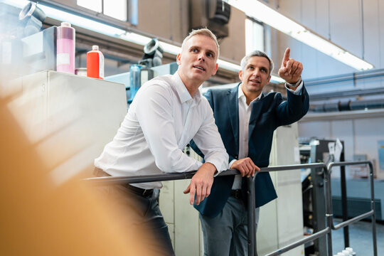 Two businessmen talking in a factory - Powered by Adobe