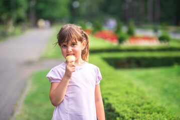 Fototapeta premium Little girl enjoying ice cream cone in summer park
