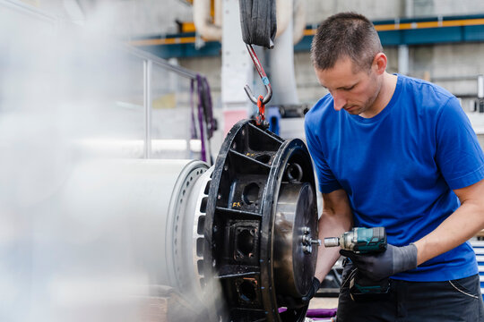 Professional male technician fastening nut with equipment in industry