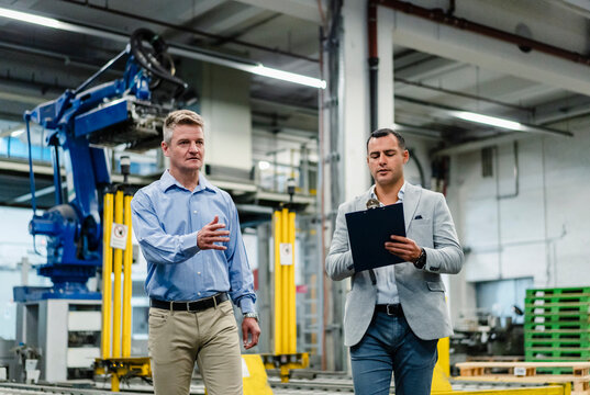 Male supervisor discussing with manger while walking in industry