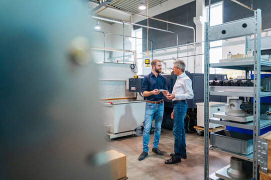 Two people discussing in a production hall with machinery