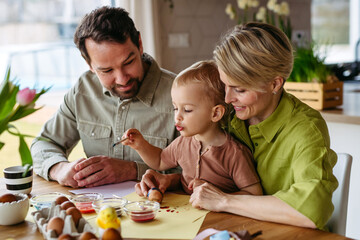 Family decorating easter eggs at home.