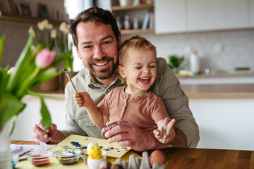 Little boy and father painting eggs with brush and easter egg dye.