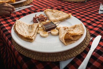 Tourists enjoying pancakes with sliced banana, bacon and maple syrup for breakfast during a cultural trip in a safari lodge in tanzania, africa
