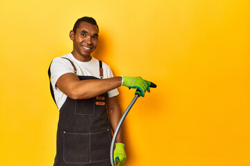 African American gardener with plant and hose, yellow studio setting.