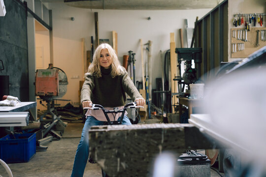 Mature woman riding a bike in a workshop showcasing her passion and skill