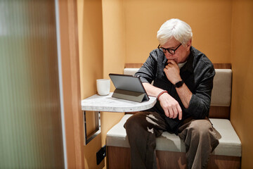 Man working on a report using a tablet in a small sitting space