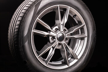 wheel. black background. car wheel with tire. disk is smelted from titanium. close-up. there is...