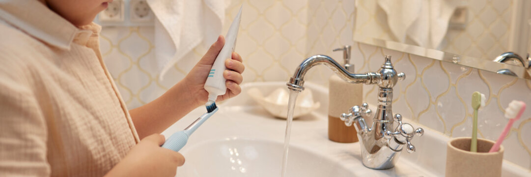 Child brushing teeth in a bathroom with running water
