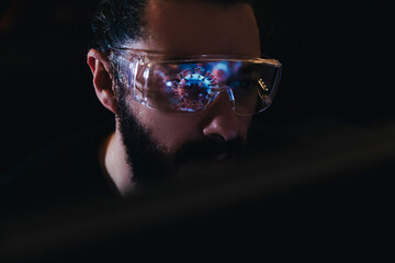 Scientist observing virus reflection in glasses in a dark laboratory setting