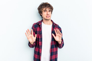 Young caucasian man isolated on blue background rejecting someone showing a gesture of disgust.
