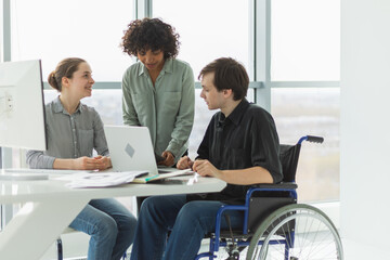 Teamwork brainstorm. Diverse multiracial colleagues man in chair for people with disability working...