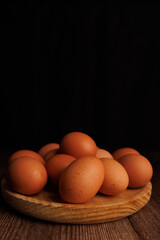 A wooden plate with several brown eggs resting on a dark wood table, showing the effects of inflation on food