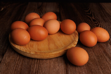 Brown eggs in wooden dish on dark wooden surface, symbolizing economic inflation and food cost increases