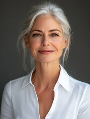 Happy and smiling mature 50 year old female psychologist poses for portrait looking at camera. Close up headshot of sophisticated businesswoman isolated on grey background advertising products and se