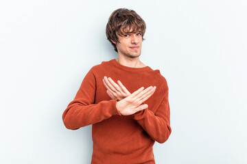 Young caucasian man isolated on blue background doing a denial gesture