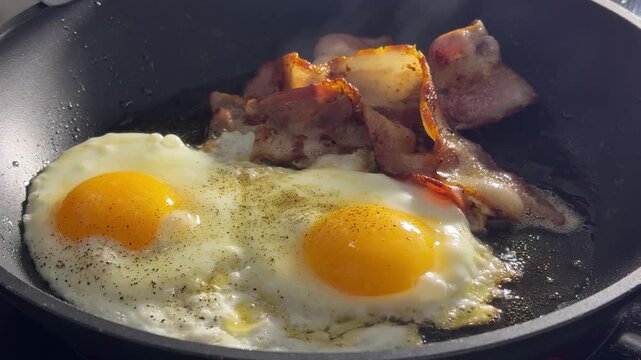 Fried eggs with fried bacon in a large frying pan